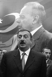 Azerbaijani President Ilham Aliyev before a poster of Heydar Aliyev.